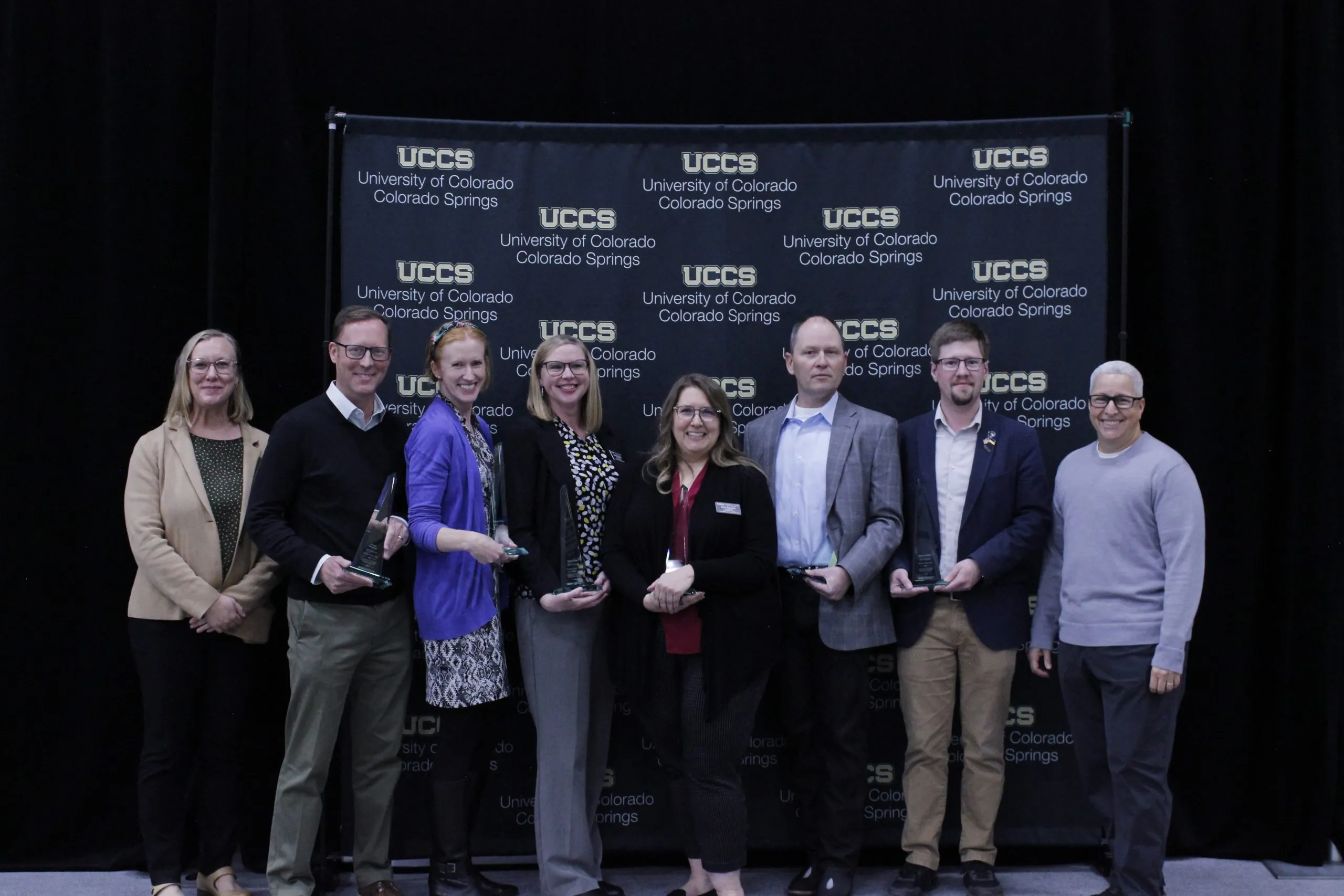 Group of people standing in front of UCCS banner.