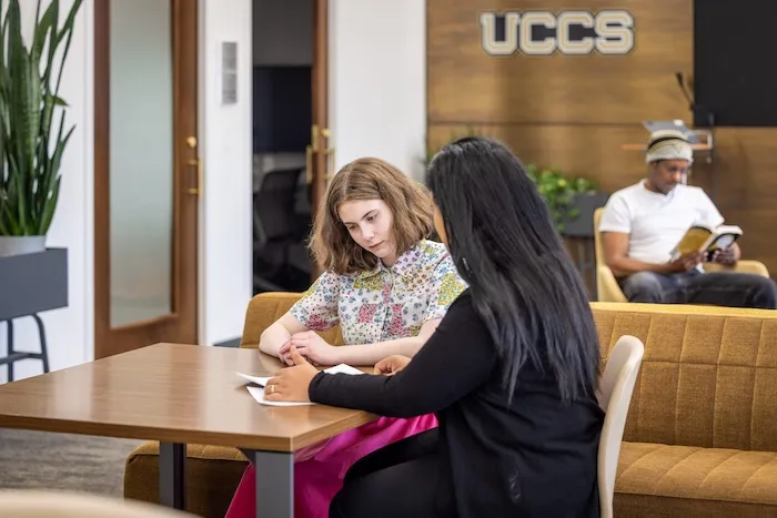 Two people at a desk going over paperwork 